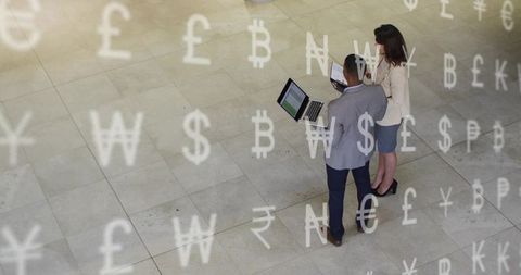 Business professionals collaborating over laptops with floating currency symbols