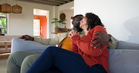 Close multiracial couple relaxing and embracing on couch