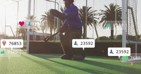 Crouching Field Hockey Goalkeeper Wearing Full Pads on Sunlit Turf with Social Overlays