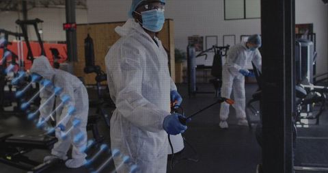 Sanitation Crew Spraying Gym Equipment Wearing Full PPE for Deep Disinfection and Safety