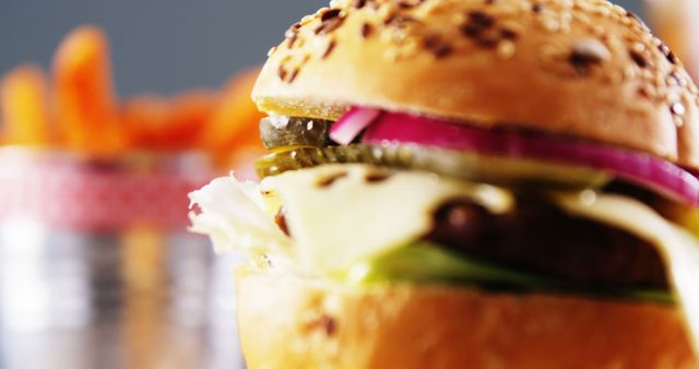 Close-up of a gourmet hamburger featuring fresh lettuce, pickles, onion, and melted cheese enveloped in a sesame seed bun. The vivid colors and textures make it appealing for use in advertisements, restaurant menus, food blogs, or social media posts focused on dining and fast food.