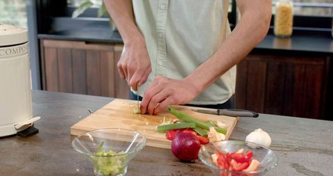 Man Preparing Fresh Vegetables with Professional Chef's Knife in Modern Home Kitchen