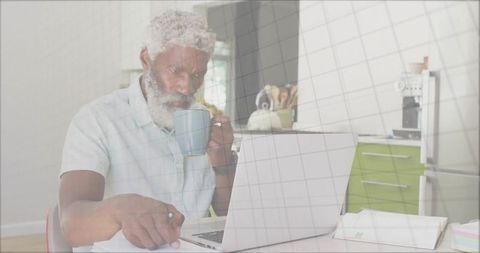 Elderly Man Enjoying Modern Home Office Setup in Bright Kitchen