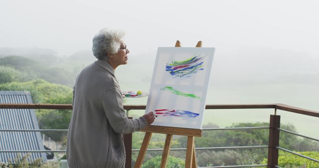 African american senior woman painting on canvas in the balcony at home. retirement senior lifestyle living in quarantine lockdown concept