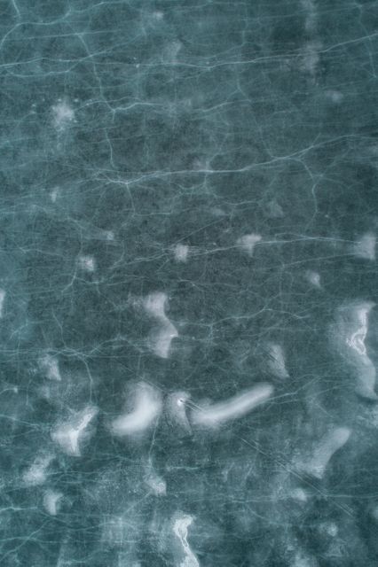 Close-up view of a frozen surface featuring light cracks and texture. Ideal for use in advertisements related to winter sports, cold weather themes, and nature backgrounds. Suitable for environmental discussions, articles on climate phenomena, and artistic projects highlighting natural beauty and abstract patterns.