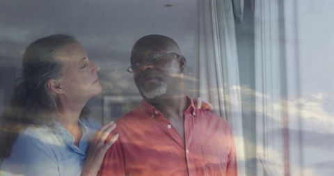 Senior Couple Relaxes in Sunlit Living Space with Scenic Window View
