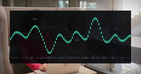 Typing woman in bright pink blazer working on laptop with data overlay in modern office