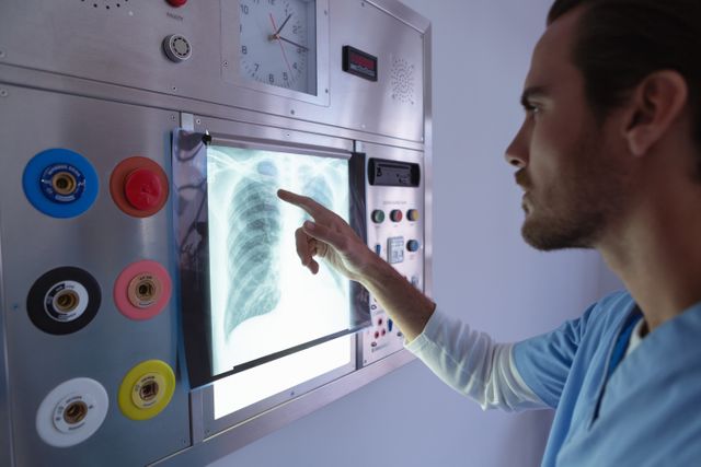 Side view of male surgeon examining x-ray on x-ray light box in operation room at hospital