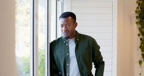 Man relaxing by large window at home in natural light