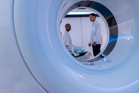 African woman receiving mri scan while asian male clinician preparing scanner in radiology
