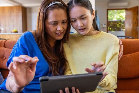 Mother and daughter using tablet device at home