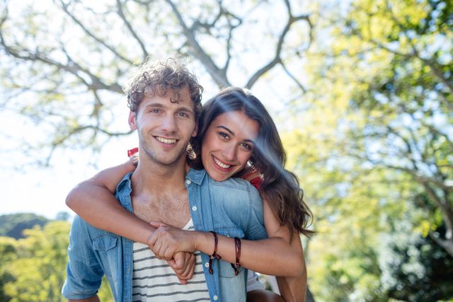 Portrait of young couple smiling and embracing in park on a sunny day