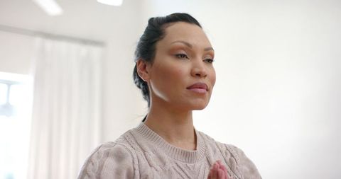 Asian Woman Pressing Hands in Quiet Room with Natural Light