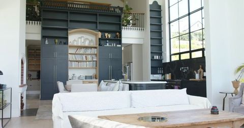 Sunlit modern open-plan living room with white slipcover sofa and dark blue cabinetry