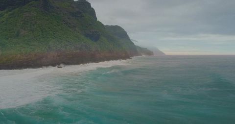 Misty Turquoise Sea Caressing Rugged Emerald Cliffs Along Remote Rocky Shoreline