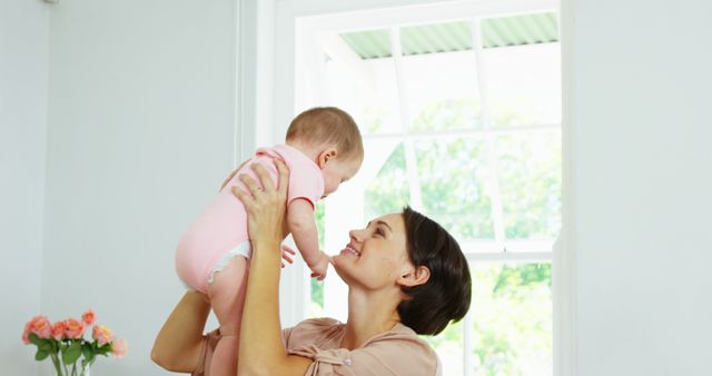 Happy Mother Holding Baby Near Bright Window at Home - Download Free Stock Images Pikwizard.com