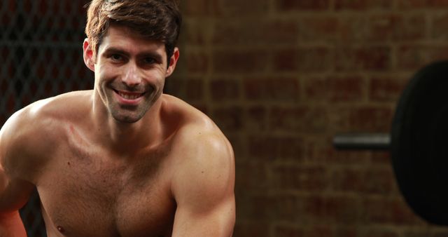 Fit young man smiling during workout, providing inspiration for exercise routines. Suitable for fitness blogs, gym advertisements, health magazines, motivational posters and athletic apparel promotions.