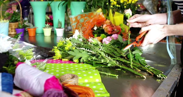 Florist hands trimming flower stems while arranging a colorful bouquet at a flower shop counter with vibrant decoration materials. Suitable for illustrating floral business, professional floristry, flower arrangement tutorial, or promotional material for flower shops.