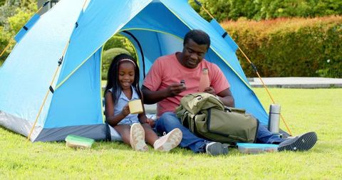 Father and Daughter Camping with Blue Tent Enjoying Nature