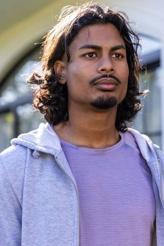 Indian young man looking up with confident expression wearing hoodie outdoors