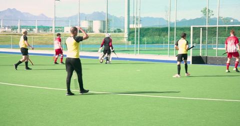 Diverse Male Players Competing in Field Hockey Match