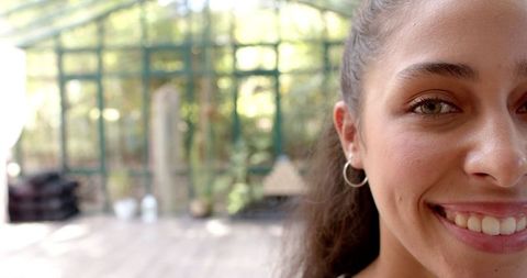 Smiling Woman in Tranquil Glass House Enjoying Mindfulness