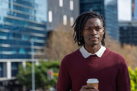 Contemplative young african american professional holding coffee cup in urban business district