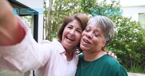 Mature women taking joyful selfie in garden patio, candid companionship moment