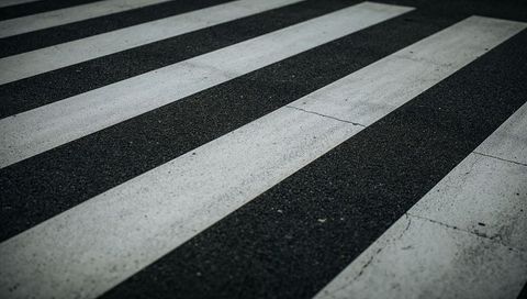Running diagonal crosswalk stripes on weathered asphalt with cracked paint texture