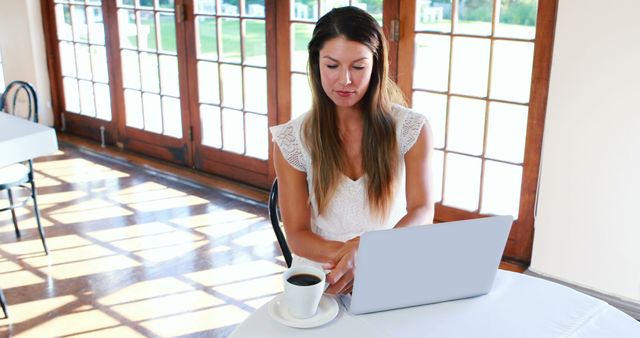 Woman Working on Laptop in Sunlit Cafe with Coffee - Download Free Stock Images Pikwizard.com