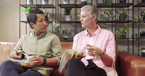 Colleagues sharing meal in plant-filled lounge