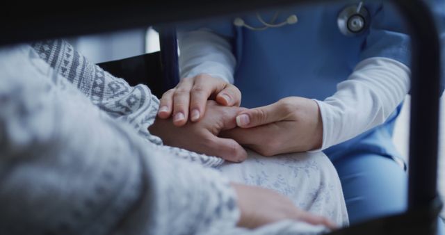 Healthcare professional in blue uniform holding patient's hand gently, showing support and compassion. Ideal for medical and healthcare articles, advertisements, promoting patient care, compassionate healthcare, and empathetic doctor-patient relationships.