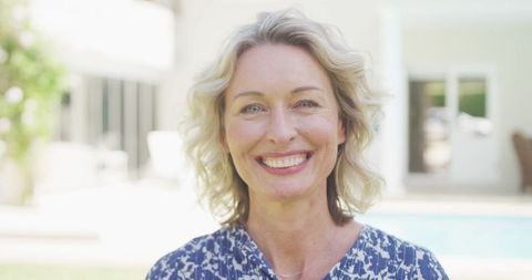 Smiling Middle-aged Blonde Woman Relaxing at Home by Pool