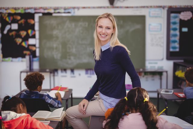 Portrait of teacher helping schoolkids with their homework in classroom at school