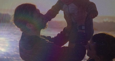 Family Enjoying Sunset at Beach with Baby Raised in Air