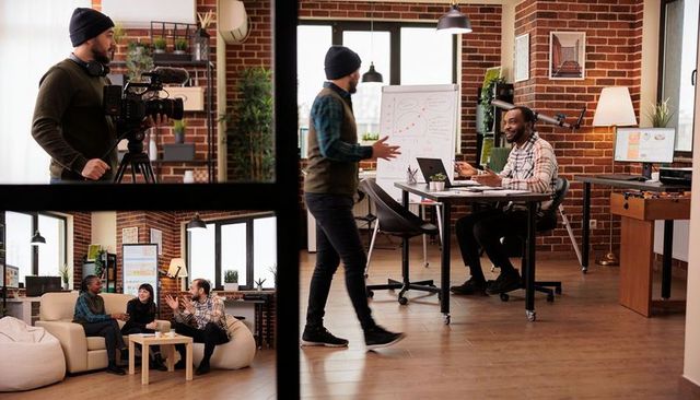 Team collaborating in industrial loft, presenter walking and gesturing while cameraman films