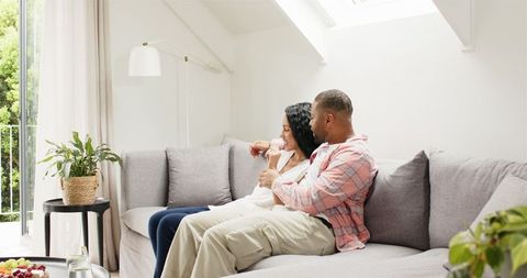 Happy Couple Sharing Engagement News Via Smartphone on Sofa