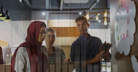 Multicultural team including woman wearing headscarf discussing cloud analytics on whiteboard