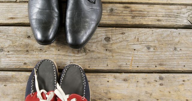 Two contrasting pairs of shoes placed on wooden flooring. This visual demonstrates the difference between formal dress shoes and casual nautical shoes with red accents, offering a comparison of styles. It could be used in articles, advertisements, or educational materials about fashion choices, footwear options, or lifestyle contrasts.