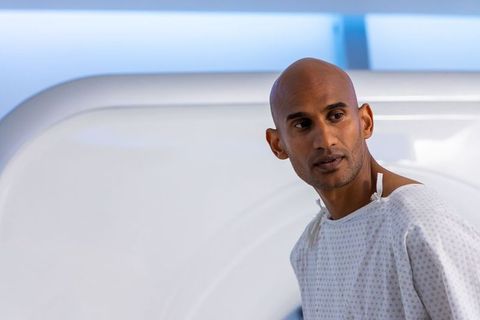 African man standing in mri room wearing hospital gown looking left radiology patient