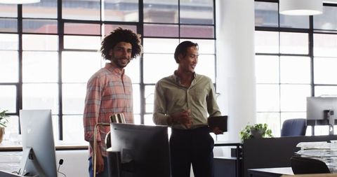 Two colleagues discussing work in modern office
