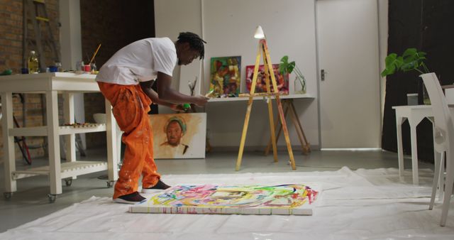 African american male artist pouring paint with a paint brush on canvas at art studio. art, hobby and creative occupation concept