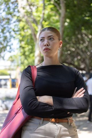 Confident african american woman standing arms crossed carrying red tote wearing black top outdoors