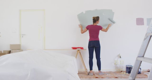 Caucasian woman painting wall with gray paint. Lifestyle, domestic life, house interior and work, unaltered.