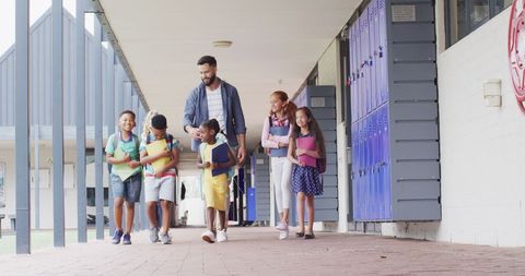 Happy Teacher with Diverse Students Walking at School