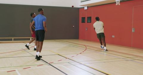 African american teammates jogging across indoor basketball court training passing drill