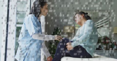 Caregiver comforting senior woman with knee pain on sofa with binary code digital health