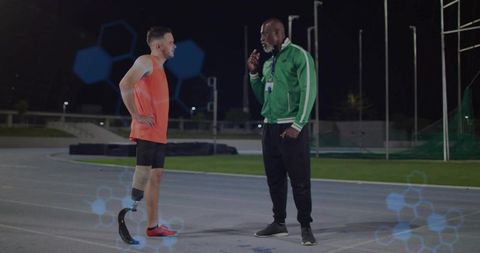 Coach motivating prosthetic athlete on nighttime track