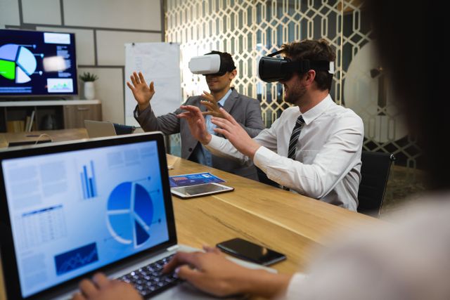 Businessmen using virtual reality headset in conference room at office