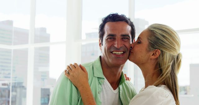 Slow motion of smiling woman kissing on mans cheek in living room at home - Download Free Stock Photos Pikwizard.com